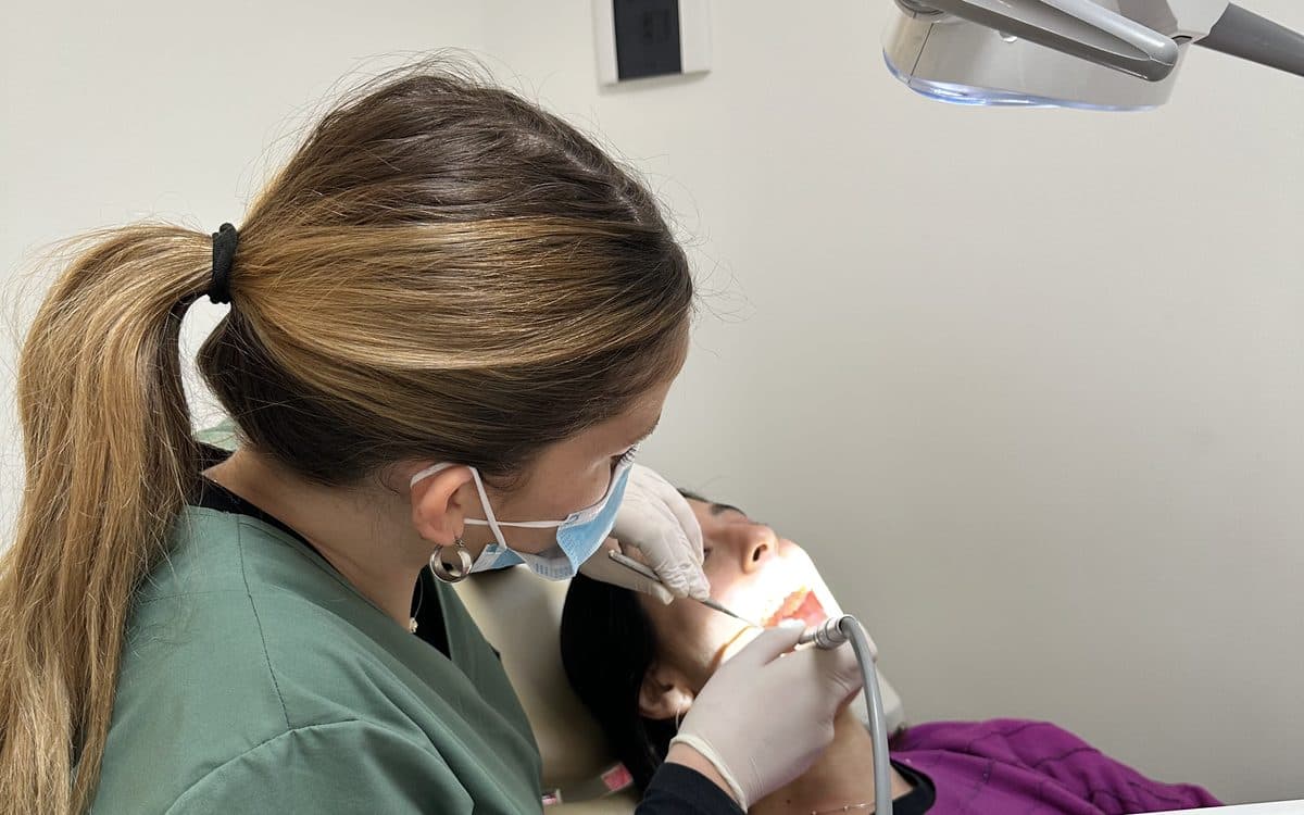 Odontóloga de Smile Lab realizando una limpieza dental a una paciente en el consultorio.